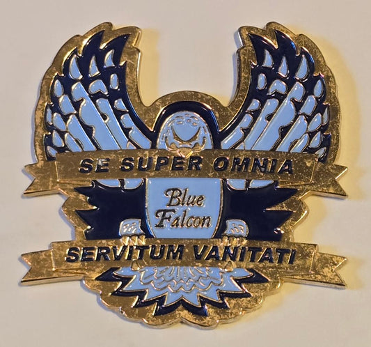 Decorative emblem with blue falcon design and gold text on a light gray background