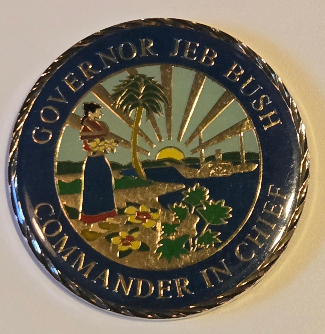 Circular emblem with 'Governor Jeb Bush Commander in Chief' text and scenic design on a white background
