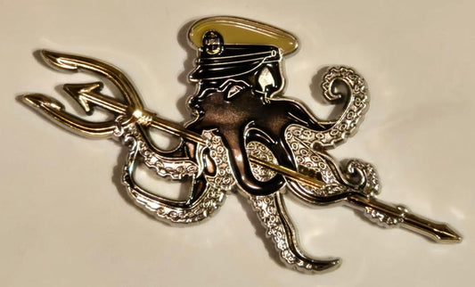 Decorative brooch with an octopus, anchor, and helmet on a beige background